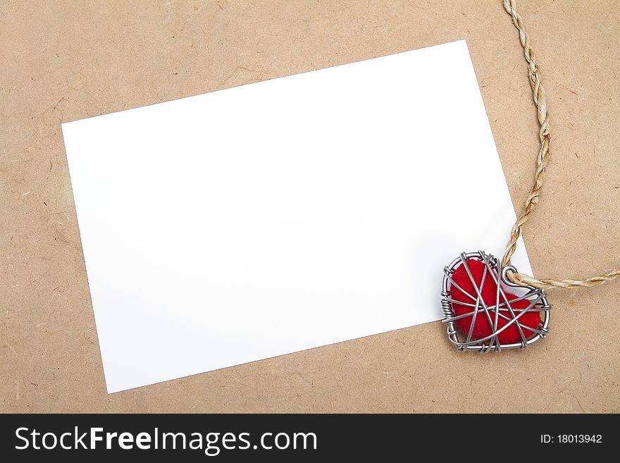 Blank greeting card and heart in wire cage on plywood background