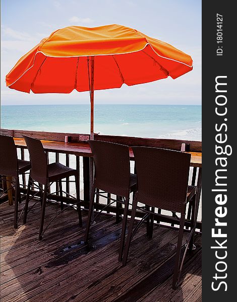 Few chairs under an umbrella on a pier with a view of the ocean