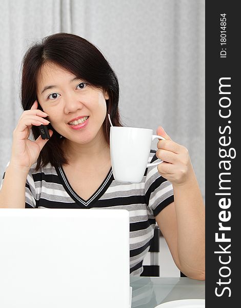 An Asian woman holding a cup of coffee while working. An Asian woman holding a cup of coffee while working