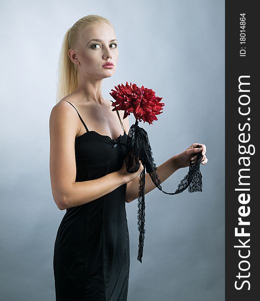 Elegant blonde girl in black dress and red flower at hand. Elegant blonde girl in black dress and red flower at hand