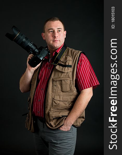 Photographer with digital kamera and zoom lens on dark background