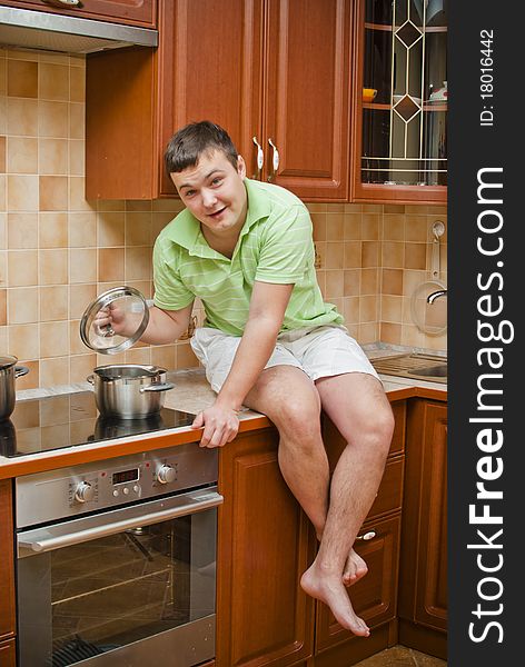 The guy in the kitchen looks into the pot. The guy in the kitchen looks into the pot