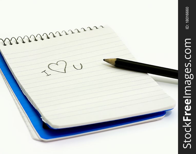 Pencil and small notebook with a love valentine message saying i love you, lying on a white surface