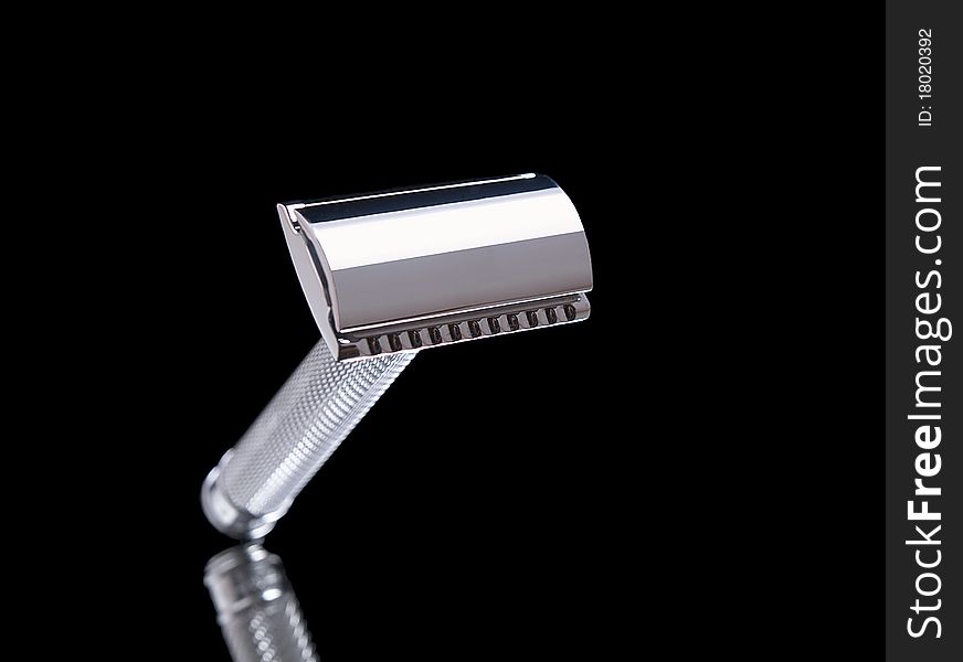 The image shows a razor over a reflective black background