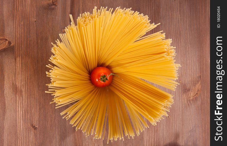 Bunch of spaghetti on a wooden table with cherry tomato. Bunch of spaghetti on a wooden table with cherry tomato