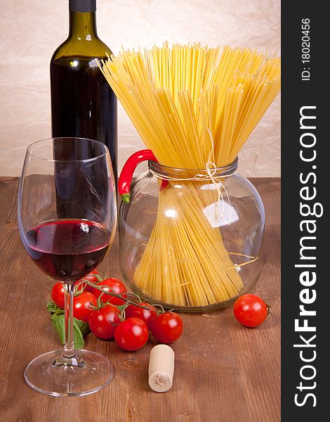 Glass of red wine near italian spaghetti and vegetables for pasta. Glass of red wine near italian spaghetti and vegetables for pasta