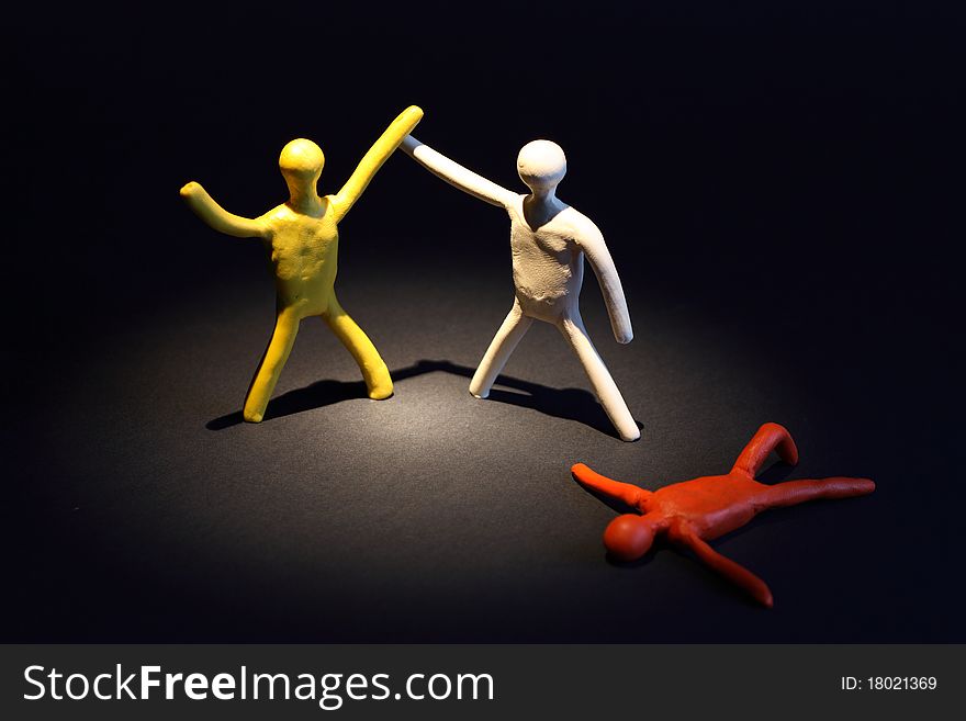 Three color plasticine men as boxers and referee on dark background. One boxer is lying and other is winner. Three color plasticine men as boxers and referee on dark background. One boxer is lying and other is winner