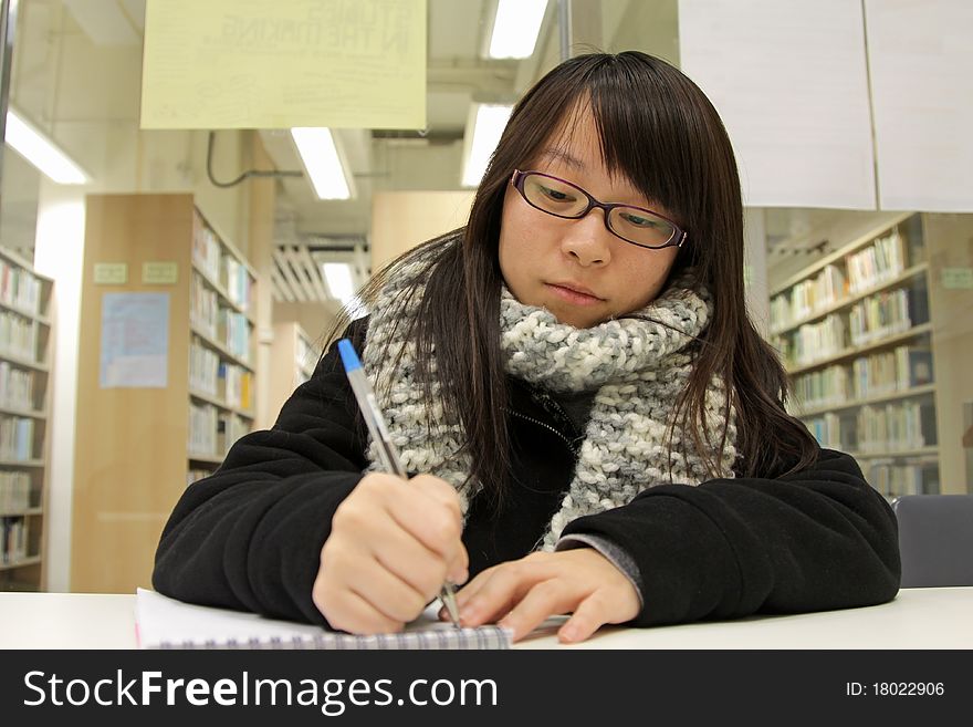 An Asian girl who is reading and studying