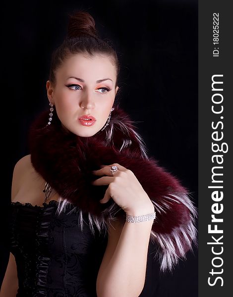 Portrait of beautiful young girl in fur collar on black background