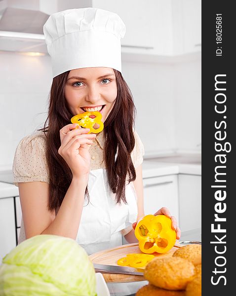 Beautiful young cook with vegetables in the kitchen