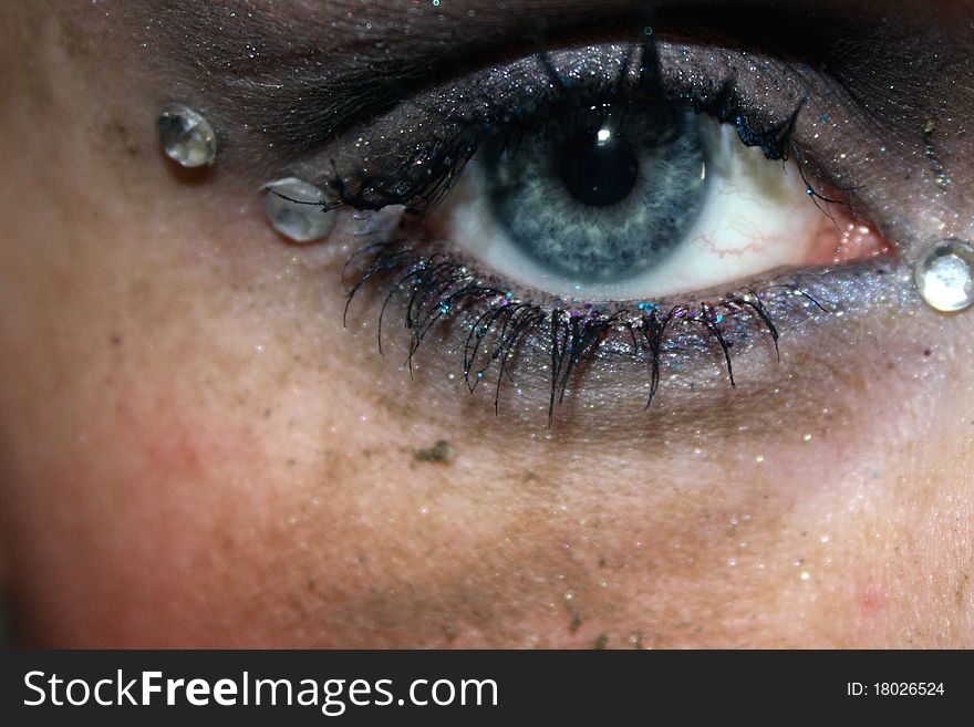 A blue eye with gems in corners and dirt on the face. A blue eye with gems in corners and dirt on the face