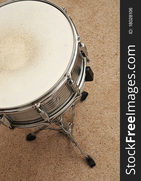 Above view of a snare drum on a stand on a carpet.