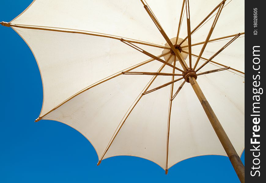 Under a white bamboo umbrella bright sky. Under a white bamboo umbrella bright sky