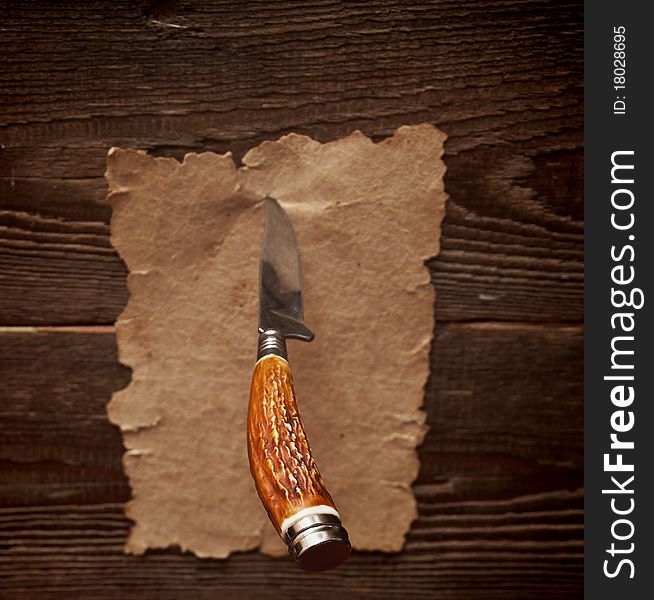 Old paper pinned to a wooden wall with a knife