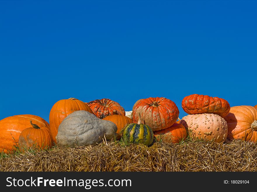 Several pumpkins on bales of straw (hay) against the blue cloudless sky