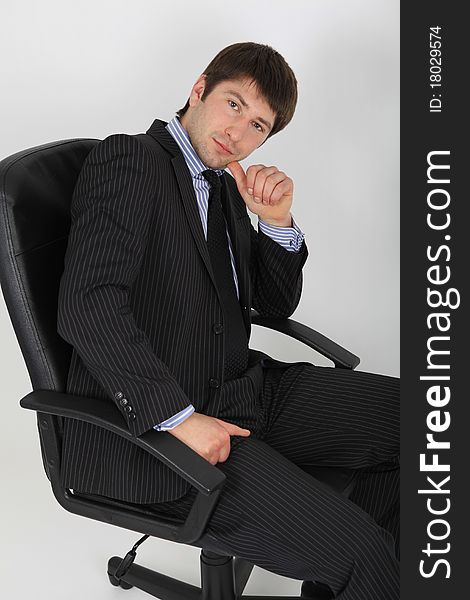 A young man in business suit sitting on a chair in a pensive pose