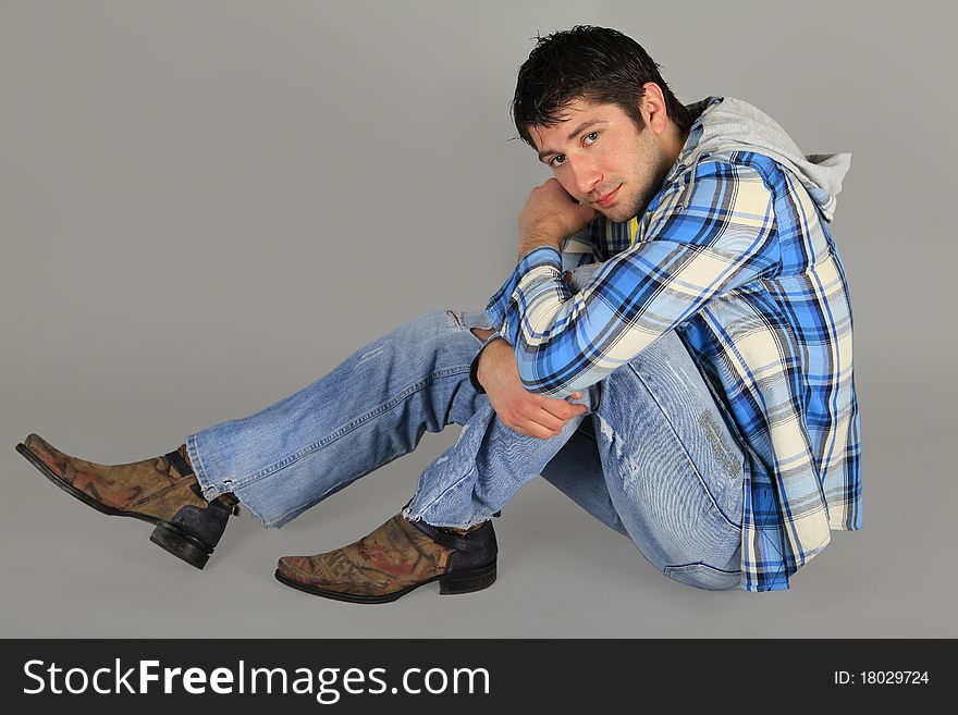 Man in jeans and a plaid shirt sitting on the floor