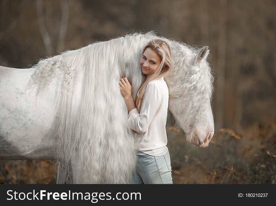Beautiful young woman with white tinker cob in an autumn field