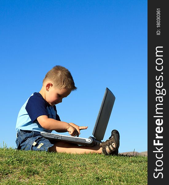 Little boy playing with laptop against blue sky. Little boy playing with laptop against blue sky