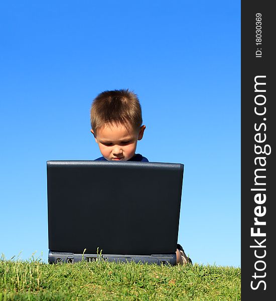 Little boy with laptop against blue sky