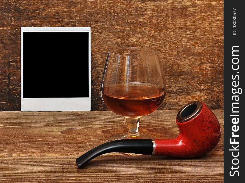 Old photo, pipe and glass of cognac on wood background