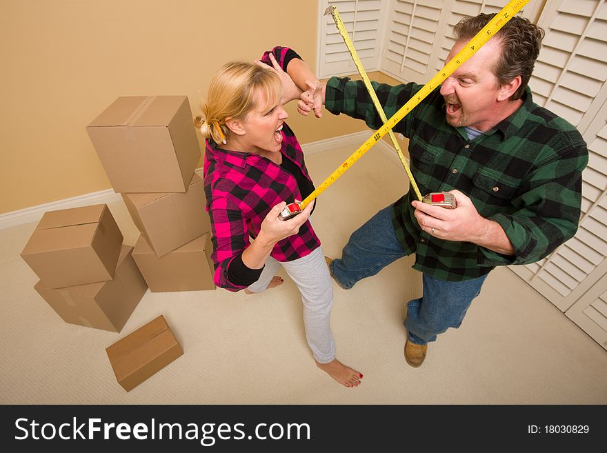 Couple Having a Fun Sword Fight with Their Tape Measures Surrounded by Packed Moving Boxes. Couple Having a Fun Sword Fight with Their Tape Measures Surrounded by Packed Moving Boxes.