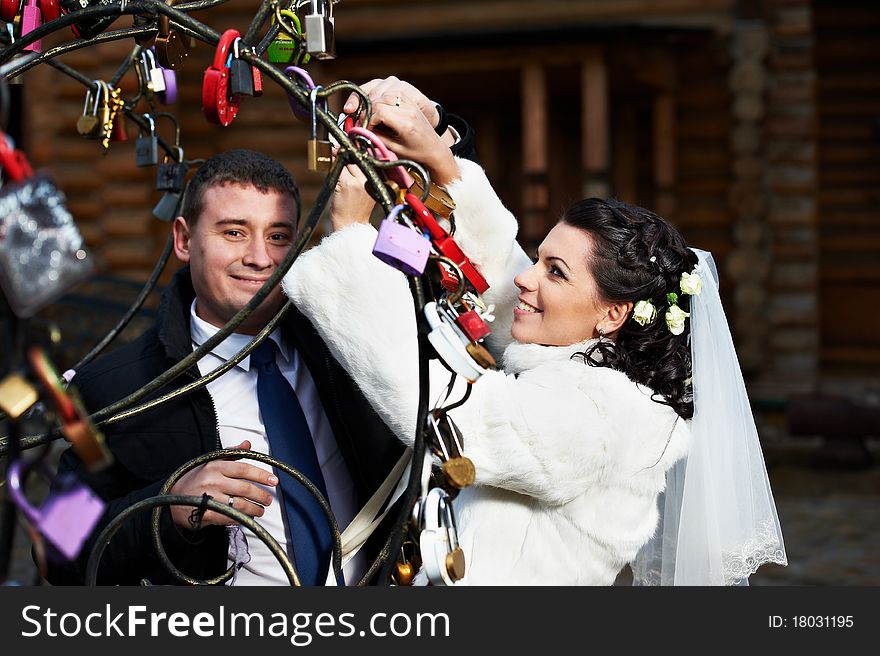 Happy bride and groom near metal tree with symbol lock at a wedding a walk in Moscow