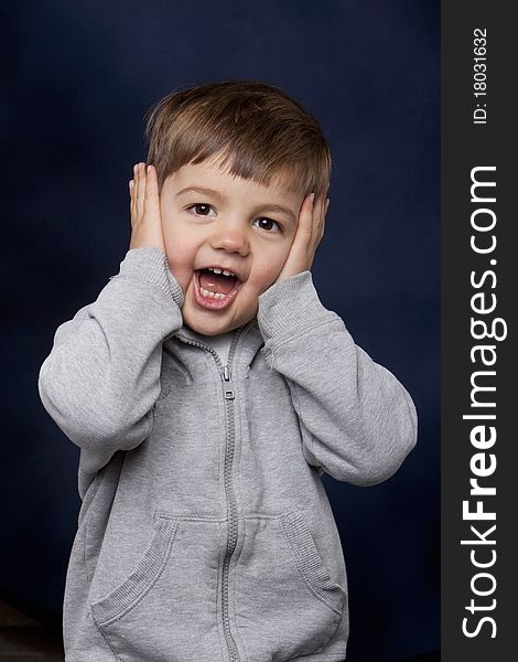 Toddler-aged boy with hands over his face and a surprised expression. Toddler-aged boy with hands over his face and a surprised expression.