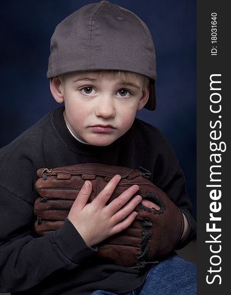 Young boy with a baseball hat and glove and a sad expression. Young boy with a baseball hat and glove and a sad expression.