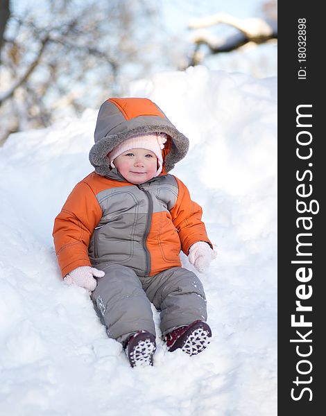 Adorable baby sliding down from hill through deep snow