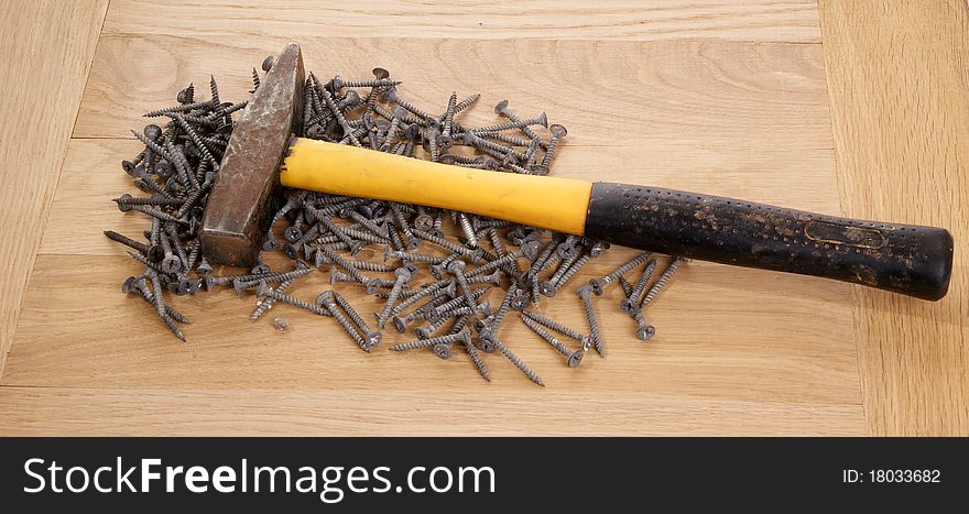 A pile of old screws and a hammer closeup to the background of the tree