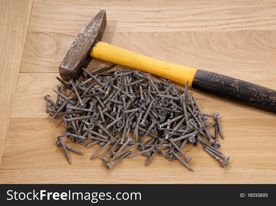 A pile of old screws and a hammer closeup to the background of the tree