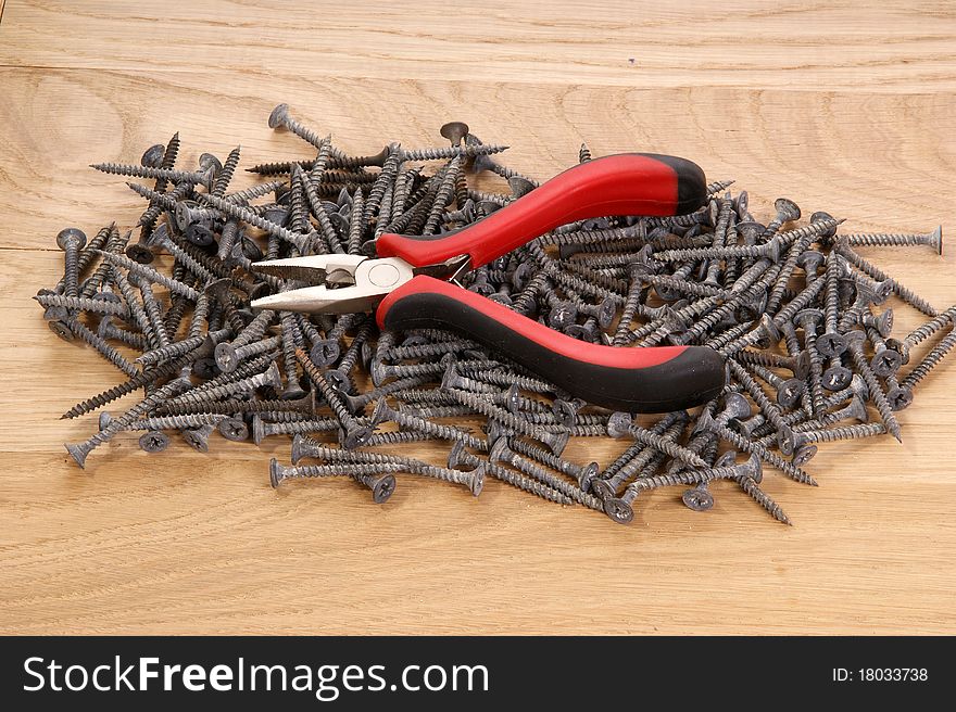 A pile of old screws and pliers closeup to the background of the tree