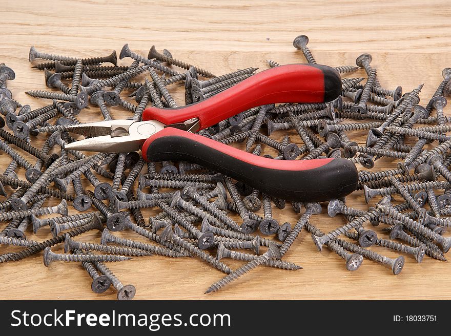 A pile of old screws and pliers closeup to the background of the tree