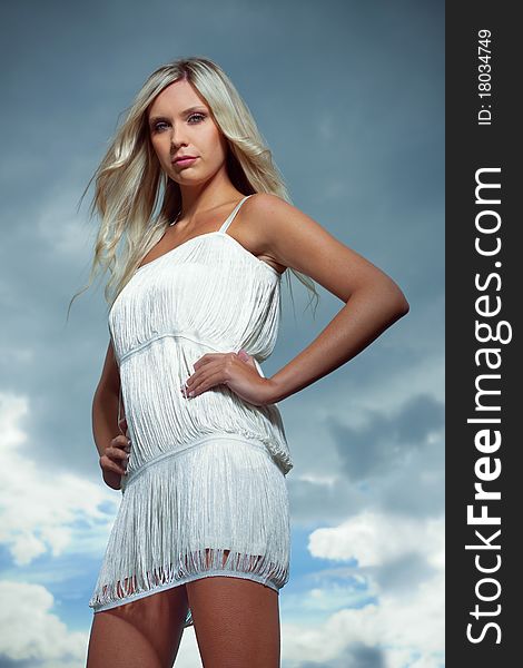Attractive blond girl in white dress, blue dramatic sky