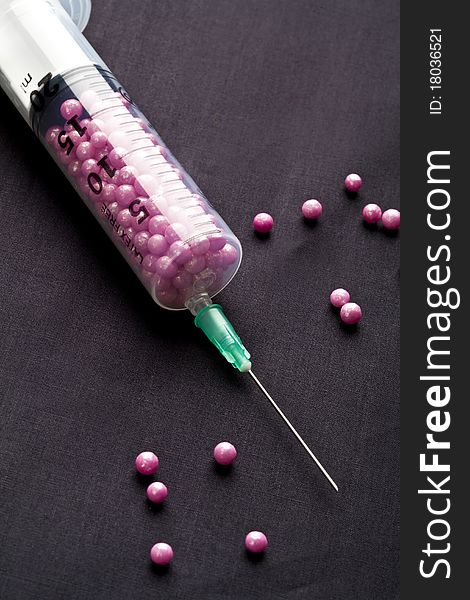 Syringe filled with pink candy on a black background