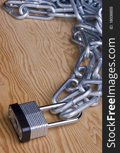 Metal lock and chain on a wooden background. Add your text to the background.