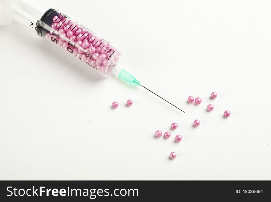 Syringe filled with pink candy on a white background