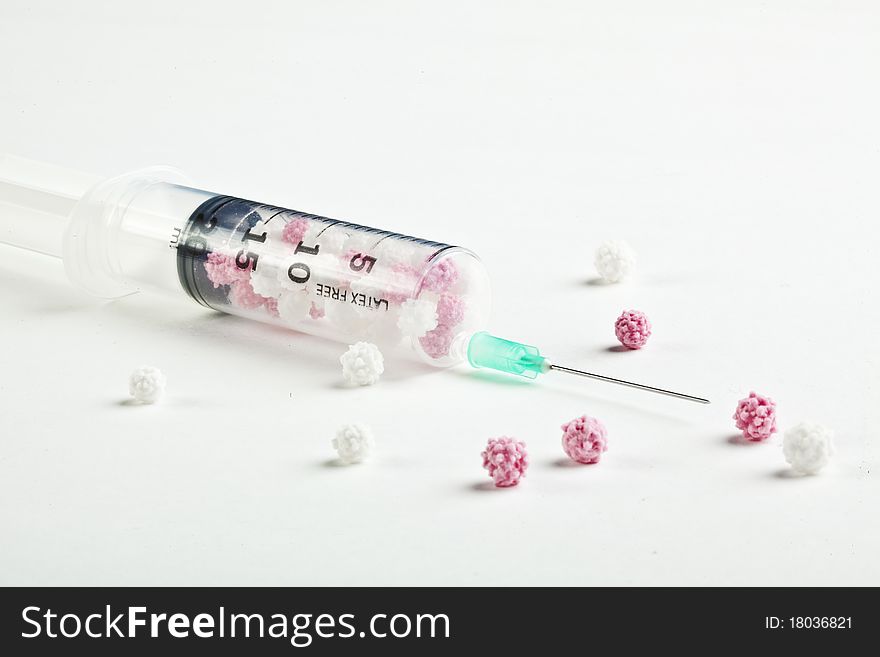 Syringe filled with heart shaped candy on a white background