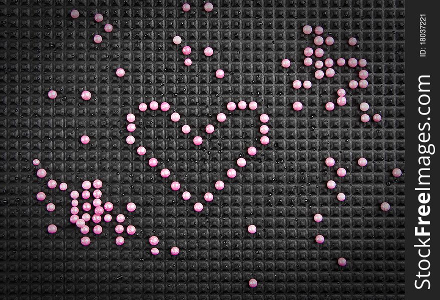 Heart shape made with candy on rubber black background