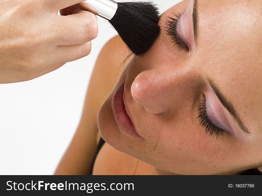 Close up of the face of a young model with a makeup artist applying blush with a concealer foundation brush. Close up of the face of a young model with a makeup artist applying blush with a concealer foundation brush