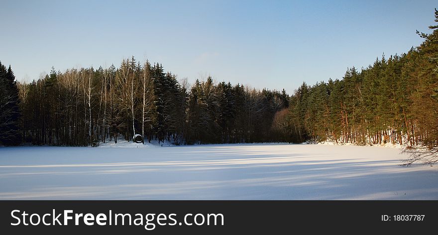Winter meadow with log cabin in the Czech forest
