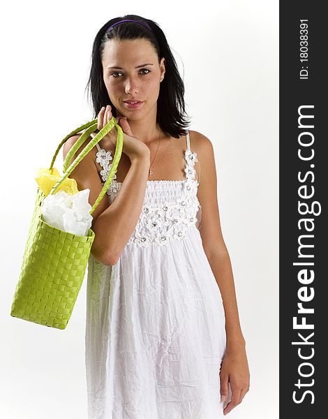 Young tanned healthy woman in a white summer cotton dress and yellow sandals carrying a green woven shopping bag across her shoulder. Young tanned healthy woman in a white summer cotton dress and yellow sandals carrying a green woven shopping bag across her shoulder