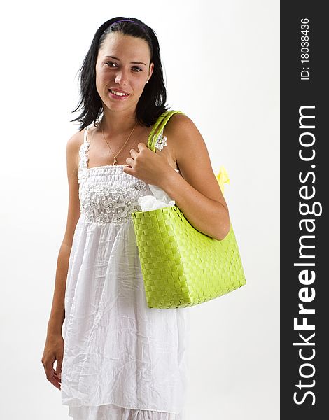 Young tanned healthy woman in a white summer cotton dress and yellow sandals carrying a green woven shopping bag across her shoulder. Young tanned healthy woman in a white summer cotton dress and yellow sandals carrying a green woven shopping bag across her shoulder