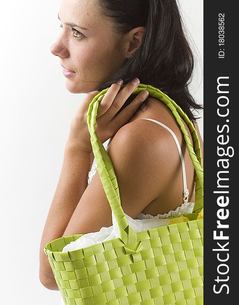 Young tanned healthy woman in a white summer cotton dress holding a green woven shopping bag over her shoulder. Young tanned healthy woman in a white summer cotton dress holding a green woven shopping bag over her shoulder