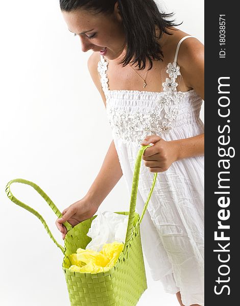 Young tanned healthy woman in a white summer cotton dress looking surprised inside a green woven shopping bag. Young tanned healthy woman in a white summer cotton dress looking surprised inside a green woven shopping bag