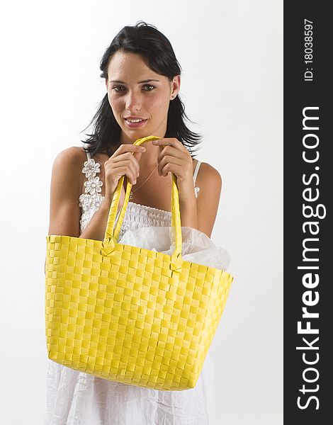 Young tanned healthy woman in a white summer cotton dress holding a yellow woven shopping bag in front of her. Young tanned healthy woman in a white summer cotton dress holding a yellow woven shopping bag in front of her