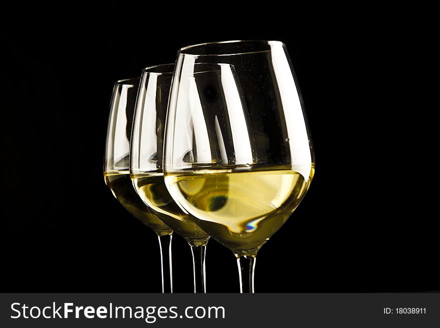 Three glasses of white wine on black background