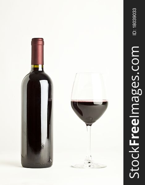 Glass of red wine and a bottle isolated over white background