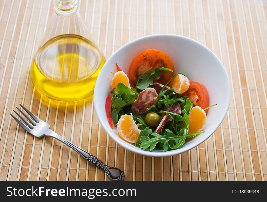 Salad greens, mandarin orange and salami in a white plate. Salad greens, mandarin orange and salami in a white plate.